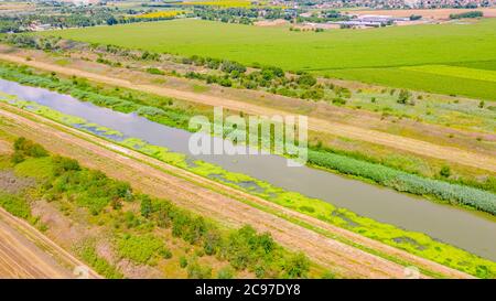 Au-dessus de la vue sur une partie de la rivière, canal qui va entre les champs agricoles, système d'irrigation, après la récolte. Banque D'Images