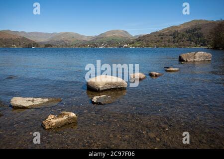 Les rives et le paysage du lac Windermere dans le district du lac lors d'une journée ensoleillée de ciel bleu au printemps. Avec des arbres sans feuilles et des chemins calmes et vides. Banque D'Images