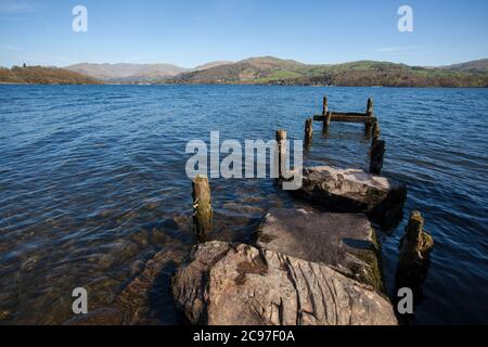 Les rives et le paysage du lac Windermere dans le district du lac lors d'une journée ensoleillée de ciel bleu au printemps. Avec des arbres sans feuilles et des chemins calmes et vides. Banque D'Images