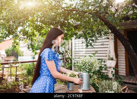 Jeune brunette avec de longs cheveux pot pot avec des fleurs sur le panier sous l'arbre vert le jour ensoleillé d'été dans le jardin Banque D'Images