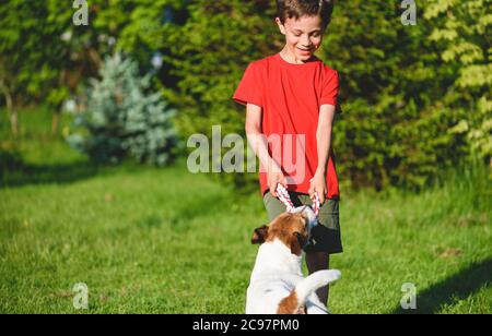 Enfant garçon jouant avec chien de chien de la guerre jeu dans le jardin arrière le jour ensoleillé d'été Banque D'Images