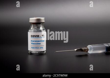 Petite bouteille de vaccin (flacon) avec une étiquette indiquant « Covid - 19 Corona virus Vaccine injection Only » et une seringue médicale isolée sur la vaccination noire Banque D'Images