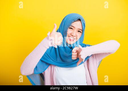 Asiatique musulman arabe, Portrait de la bonne belle jeune femme Islam religieux porter voile hijab sourire drôle elle montrant les pouces vers le haut et les pouces vers le bas difficile Banque D'Images