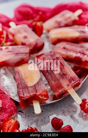 Glace à la pomme et au cassis et aux fraises popsicles dans un plateau métallique avec glaçons Banque D'Images