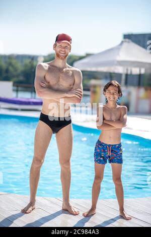 Homme et garçon en maillot de bain près de la piscine