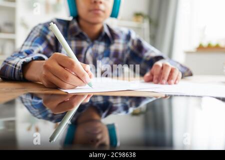 Gros plan de la tablette numérique sur la table avec un enfant assis et prenant des notes dans un ordinateur portable en arrière-plan Banque D'Images