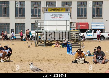 Sans surveillance, fermé, fermé Lifeguard / Life Guard Station sur une plage assez animée de Bournemouth avec des touristes, des baigneurs et des visiteurs lors d'une journée ensoleillée d'été. ROYAUME-UNI (120) Banque D'Images