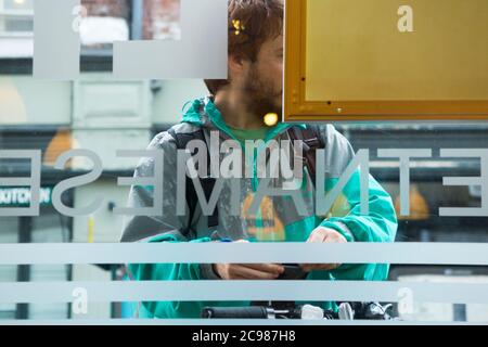 Deliveroo emporter repas courrier livraison cycliste à l'extérieur d'un restaurant d'où il fait une collection. Angleterre Royaume-Uni (120) Banque D'Images