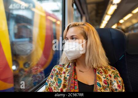 Une blonde portant un masque facial est assise dans une voiture de train à la gare de Waterloo, Londres, le 26 juillet 2020 Banque D'Images