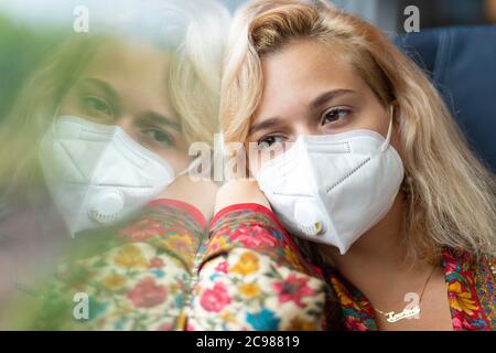 Une blonde portant un masque facial se trouve dans une voiture de train sur South Western Railway, Angleterre, le 26 juillet 2020 Banque D'Images