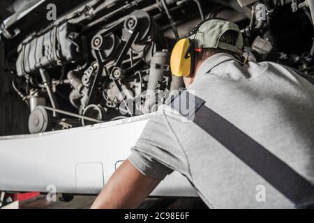 Technicien de moteurs diesel professionnel de race blanche dans ses 40 s regardant à l'intérieur du compartiment de moteur de bus essayant de localiser le problème potentiel. Banque D'Images