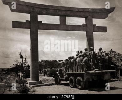 Les unités du 15e Régiment des États-Unis, 6e Division Marines, entrent dans Naha, capitale d'Okinawa par un torii, une porte japonaise traditionnelle alors que la guerre dans le Pacifique touche à sa fin en 1945. Banque D'Images