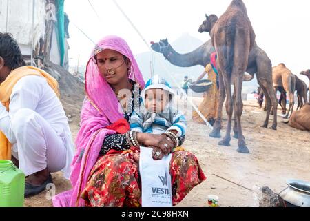 Mère prenant soin de son enfant dans ses bras au terrain d'exposition de chameau de pushkar. Banque D'Images