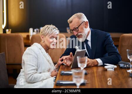 Beau couple senior regardant la même tablette dans le restaurant, concept public, caucasiens matures utilisent la technologie moderne Banque D'Images