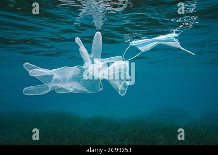 Gants et masque sous l'eau dans la mer, pollution des déchets plastiques depuis la pandémie du coronavirus COVID-19, mer Méditerranée Banque D'Images