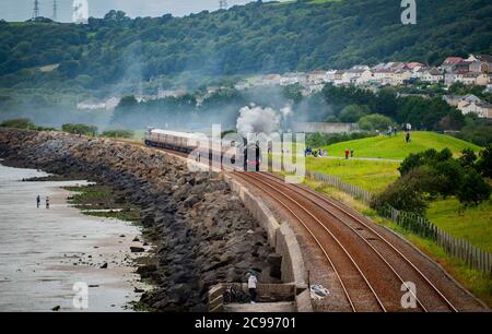 Llanelli, pays de Galles. 29 juillet 2020. Les gens regardent le moteur à vapeur Britannia 70000 se rendre le long de la magnifique ligne côtière rurale de Llanelli, tandis que la locomotive traverse le sud du pays de Galles. Depuis son retrait du service en 1966, les moteurs ont été préservés et sont maintenant la propriété de la Locomotive Royal Scot et de General Trust et transportent des passagers sur des circuits de lignes principales à travers le Royaume-Uni crédit : Robert Melen/Alay Live News Banque D'Images