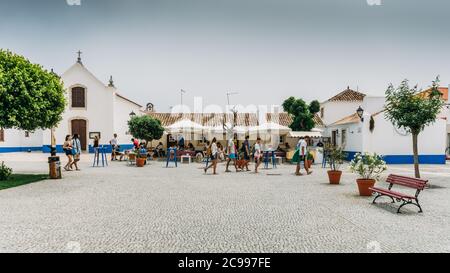 Place principale avec des personnes se détendant dans les cafés à pictureque Porto Covo au Portugal Banque D'Images