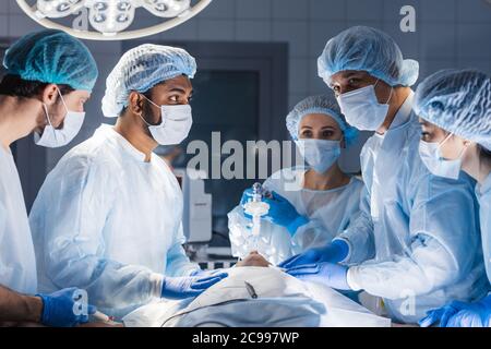Les femmes en soins infirmiers putting oxygen mask on patient en salle d'opération. Manœuvre de poussée de la mâchoire technique pour donner de l'oxygène et des médicaments par un masque de ventilateur Banque D'Images