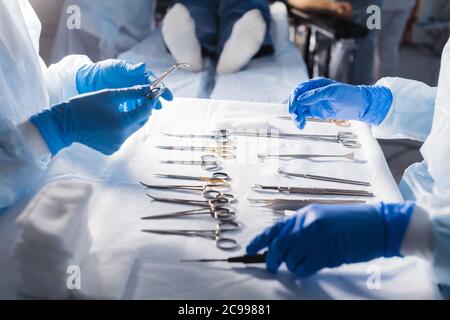 Mains de l'infirmière de la salle d'opération en gants bleus stériles choix pour le chirurgien de l'instrument nécessaire, pour effectuer la chirurgie, gros plan. Banque D'Images