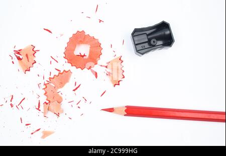 Certains matériaux d'étude contenant un crayon rouge et un taille-crayon en plastique noir isolé Banque D'Images