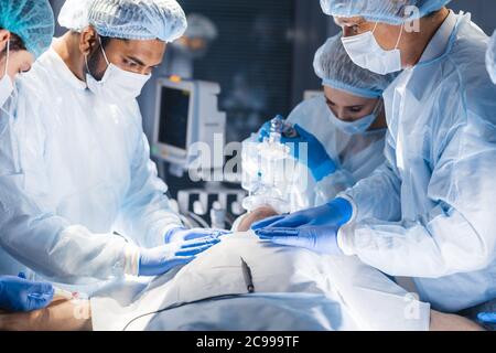 Les préparatifs de la chirurgie. La préparation de l'équipe chirurgicale de leur patient pour la chirurgie "réglage masque à oxygène sur le visage à l'theare. healthcare surgery prof Banque D'Images