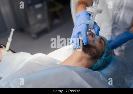 L'assistant médical faisant l'oxygénation préalable chin position montée à un patient, tenant un masque à oxygène sur son visage. Banque D'Images