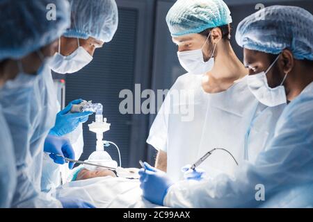 Équipe de professionnels divers surgeons performing chirurgie sur un patient à l'hôpital salle d'opération. Banque D'Images