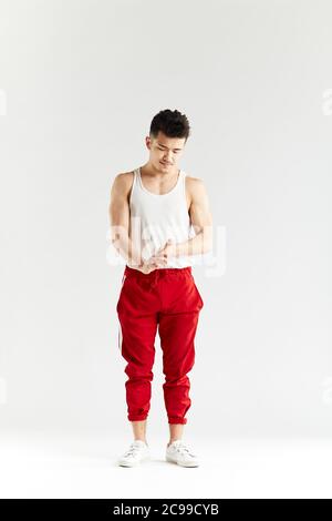 Portrait en studio de la gymnaste coréenne dans un sous-maillot blanc et un pantalon de survêtement rouge regardant l'appareil photo sur fond blanc Banque D'Images