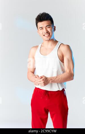 Portrait en studio de la gymnaste coréenne dans un sous-maillot blanc et un pantalon de survêtement rouge regardant l'appareil photo sur fond blanc Banque D'Images