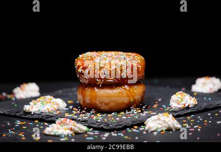 beignets au sirop de fraise et garniture colorée à la crème sur fond noir Banque D'Images