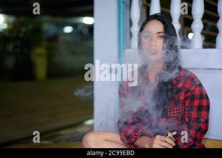 Jeune belle femme asiatique vapoing à la maison à l'extérieur Banque D'Images