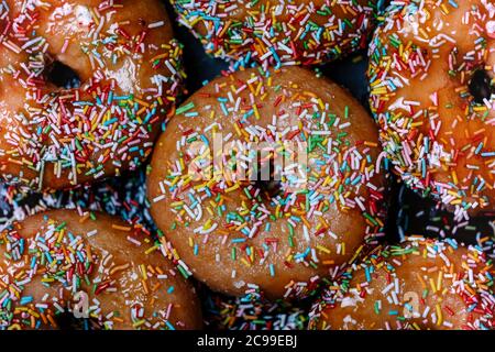 beignets au sirop de fraise et garniture colorée vue d'en haut sur fond noir Banque D'Images