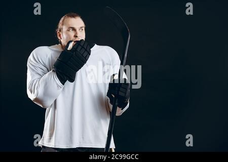 Gardien de but de hockey effrayé tenant le bâton de jeu touchant sa bouche avec la main dans le gant de protection choqué avec le but manqué. Sport, émotions humaines con Banque D'Images