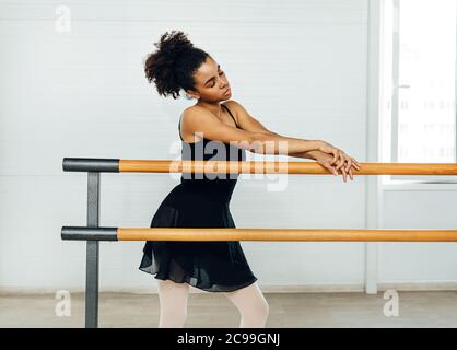 Jeune femme debout avec les yeux fermés et penchée sur barres au studio de danse Banque D'Images