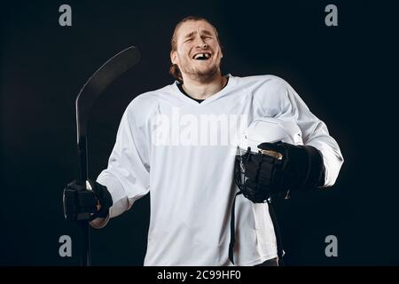 Portrait of cheerful fier caucasian hockey player smiling avec dents, à huis clos avec l'expression visage heureux et détendu, posant après la victoire Banque D'Images