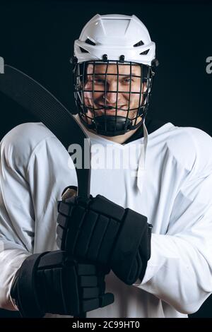 Portrait de la tête et des épaules de confiance brave joueur de hockey en uniforme blanc avec casque de protection, en veillant à son équipe s victor Banque D'Images