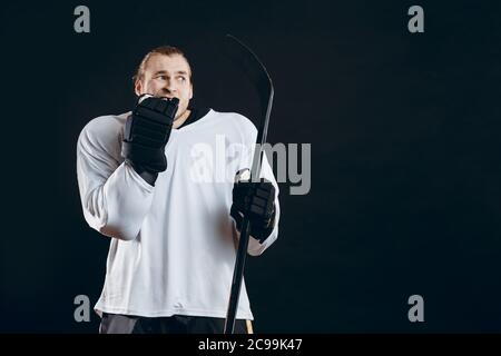 Un gardien de but de hockey effrayé tenant un bâton de jeu se morce sa main dans un gant protecteur choqué par un but manqué. Sport, émotions humaines concept. Banque D'Images