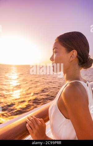 Croisière luxe voyage femme europe destination vacances. Fille profitant de la vue sur le coucher du soleil dans l'élégante robe blanche de soirée depuis le balcon suite terrasse Banque D'Images