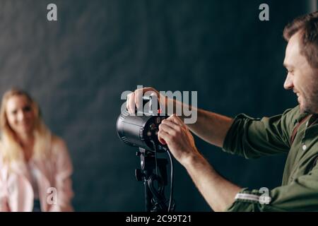 photographe contrôlant la tête d'éclairage flash du studio. gros plan. homme préparant le travail au studio Banque D'Images