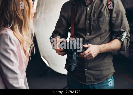 homme à la recherche de photos dans l'appareil tout en ayant une discussion avec une fille blonde , gros plan rogné photo Banque D'Images