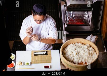 Gros plan d'un chef professionnel en gants pour faire des sushis et des petits pains dans une cuisine de restaurant.photo vue du dessus. Banque D'Images