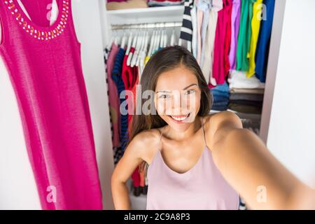 Selfie asiatique fille prenant la photo avec le téléphone mobile d'elle-même dans le dressing de placard à la maison essayant de tenue. Vêtements mode. Fille shopping Banque D'Images