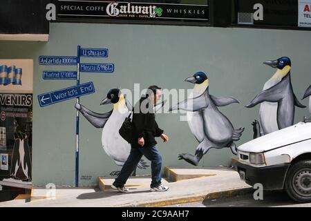 Un homme marche à côté d'un pingouin dessinant à Ushuaia, la ville la plus méridionale du monde et la capitale de la « fin du monde », Tierra del Fuego, Argentine. Banque D'Images