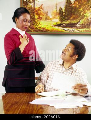 ANNÉES 1970 COUPLE AFRO-AMÉRICAIN HOMME ASSIS À TABLE PASSANT PAR LES PAPIERS DE FACTURES MÉNAGE FINANCES CHÉQUIER FEMME DEBOUT À SES CÔTÉS - KS14870 HAR001 HARS COMMUNICATION BALANCE TRAVAIL D'ÉQUIPE INFORMATION STYLE DE VIE FEMMES ÉPOUSÉ ÉPOUX SAINTETÉ VIE ASSIS COPIE ESPACE FEMMES DEMI-LONGUEUR FEMMES S'OCCUPANT HOMMES EXPRESSIONS PARTENAIRE MOUSTACHE RÊVES BONHEUR BIEN-ÊTRE FORCE MOUSTACHES AFRICAN-AMERICANS AFRICAN-AMERICAN BLACK ETHNICITÉ CHBOOK BARBE À CÔTÉ DE LUI ÉLÉGANT ADULTE MOYEN-ADULTE HOMME MOYEN-ADULTE FEMME MOYENNE-ADULTE FEMMES DE TOGETHERNESS HAR001 AFRO-AMÉRICAINS À L'ANCIENNE Banque D'Images