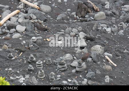 Un groupe de petits cairns, des totems de roche, sur la rive de sable noir d'Oheo Gulch dans le district de Kipahulu à Maui, Hawaii, États-Unis Banque D'Images