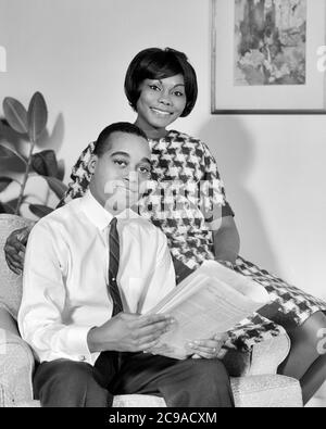 PORTRAIT DES ANNÉES 1960 COUPLE AFRO-AMÉRICAIN SOURIANT MARI FEMME ASSIS À LA MAISON REGARDANT L'HOMME DE CAMÉRA TENANT LE JOURNAL - N2233 HAR001 HARS COMMUNICATION FACIALE ÉQUILIBRE TRAVAIL D'ÉQUIPE INFORMATION FORTE JOIE HEUREUSE STYLE DE VIE FEMMES ÉPOUSÉ ÉPOUX SAINTETÉ VIE VIE VIE VIE COPIE PLEINE LONGUEUR FEMMES PERSONNES S'OCCUPANT HOMMES EXPRESSIONS B&W PARTENAIRE OEIL CONTACT SUCCÈS BONHEUR BIEN-ÊTRE GAIE FORCE AFRO-AMÉRICAINS AFRO-AMÉRICAIN NOIR ETHNICITÉ FIERTÉ À SOURIRE CONCEPTUEL JOYEUX ÉLÉGANT SOUTIEN PERSONNEL ATTACHEMENT AFFECTION ÉMOTION MI-ADULTE HOMME MI-ADULTE FEMME MI-ADULTE Banque D'Images