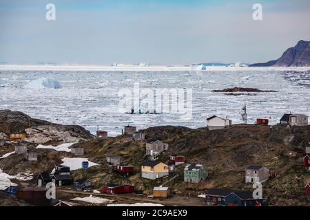 Village de Kulusuk dans l'est du Groenland. Logement Coulourful, élevé au-dessus du sol dans les styles architecturaux vernaculaires. Banque D'Images