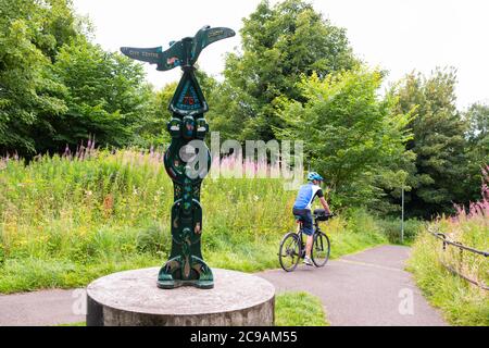 Cycliste sur ebike passant par Millenium Milepost sur National cycle Network 75, une route cyclable sustrans - Kingsknowe, Édimbourg, Écosse, Royaume-Uni Banque D'Images