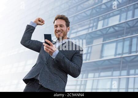 Homme d'affaires gagnant du succès gagnant sur l'application de téléphone portable. Encourager un homme d'affaires à relever un défi de jeu en ligne sur smartphone ou une offre de travail Banque D'Images