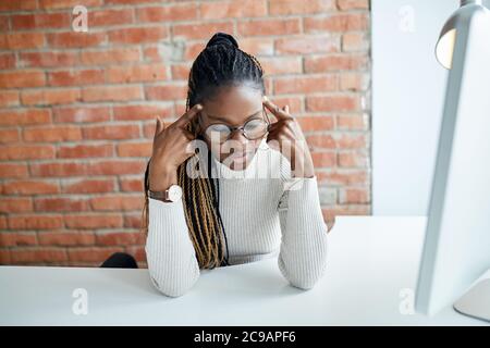 Travailleur de bureau afro fatigué ayant des maux de tête. Travailleur indépendant essayant de se souvenir de quelque chose. Mauvais souvenir. Casse-tête de fractionnement. Problèmes de santé. Gros plan. Ex Banque D'Images